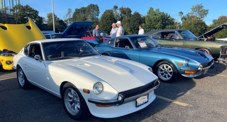 A white and blue Datsun 240Z at a car show which is a favorite of Generation X