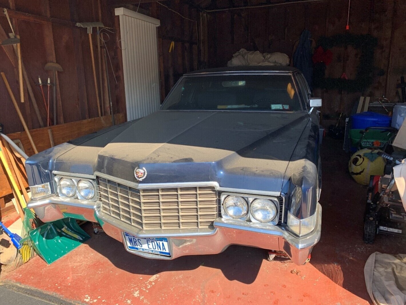 A blue dust cover Cadillac inside a garage before undertaking a DIY classic car restoration