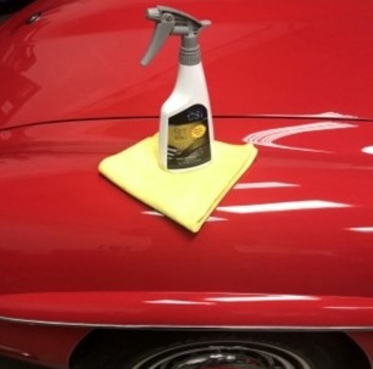A vintage car waxes sitting on top of a yellow microfiber town on a red Mercedes