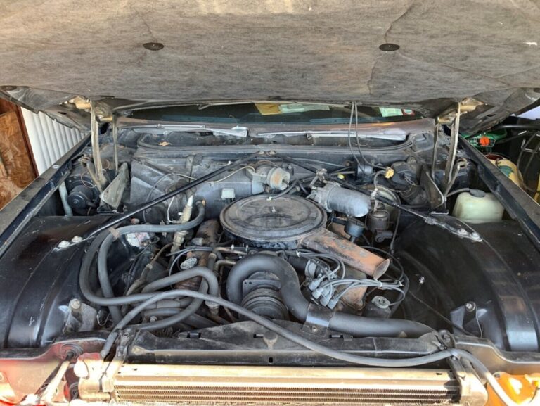 An engine compartment with the hood open in a Cadillac before undertaking a DIY classic car restoration
